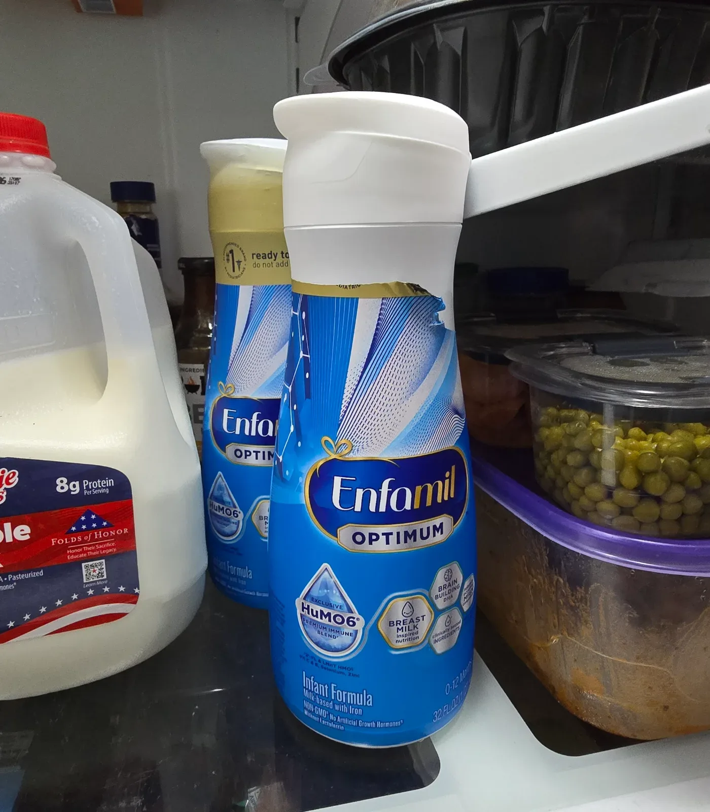 Enfamil RTF formula bottle beside a baby bottle on a nightstand with soft warm lamp lighting.