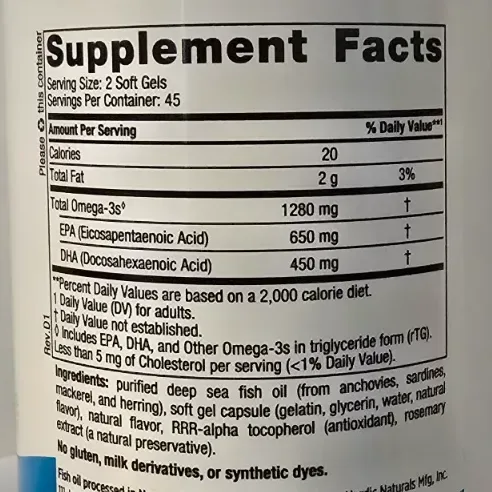 Nordic Naturals Ultimate Omega bottle open with soft gel capsules on a wooden surface in warm light