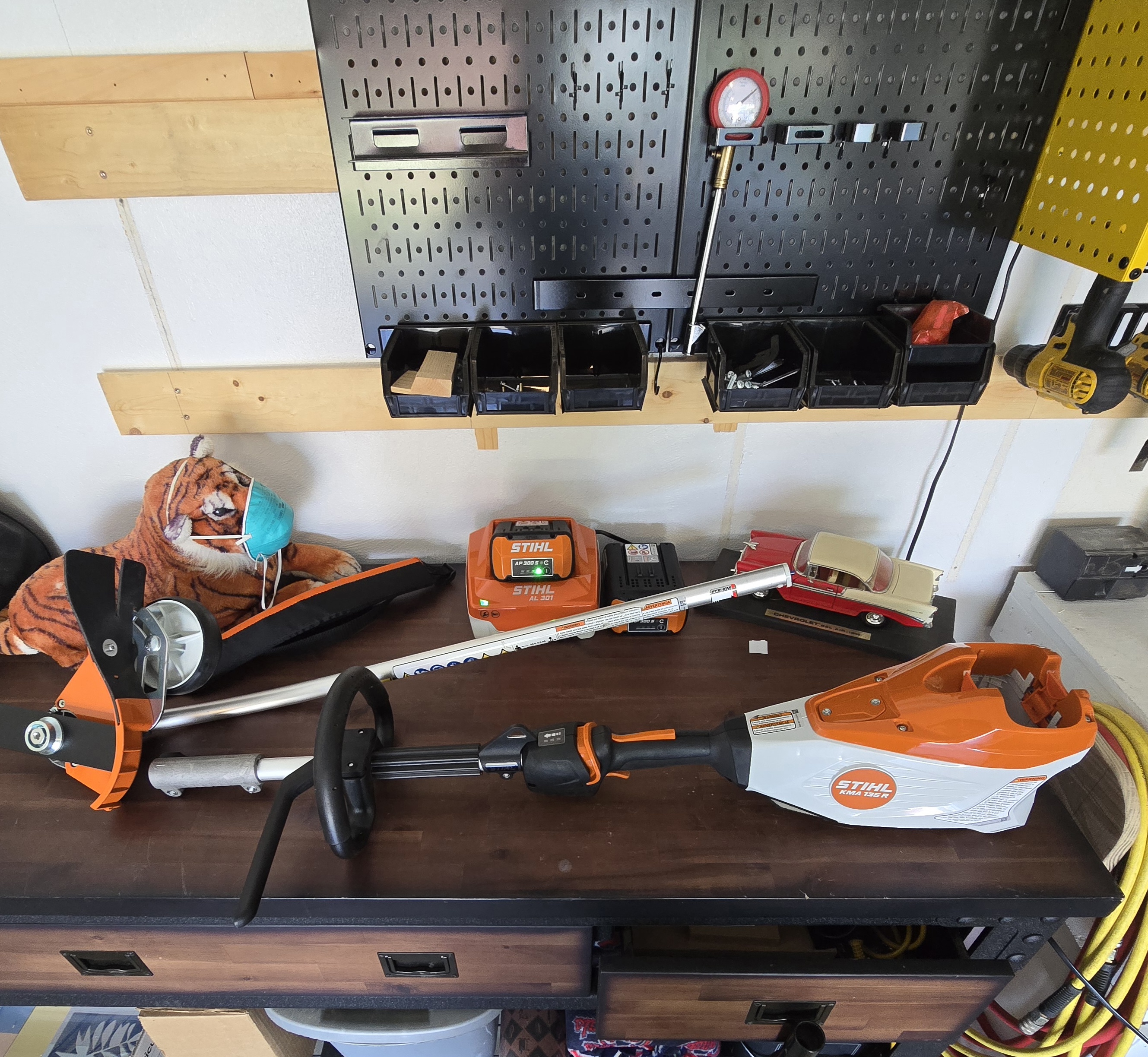 STIHL KMA 135 R power head surrounded by trimmer, edger, and hedge trimmer attachments on a clean garage floor