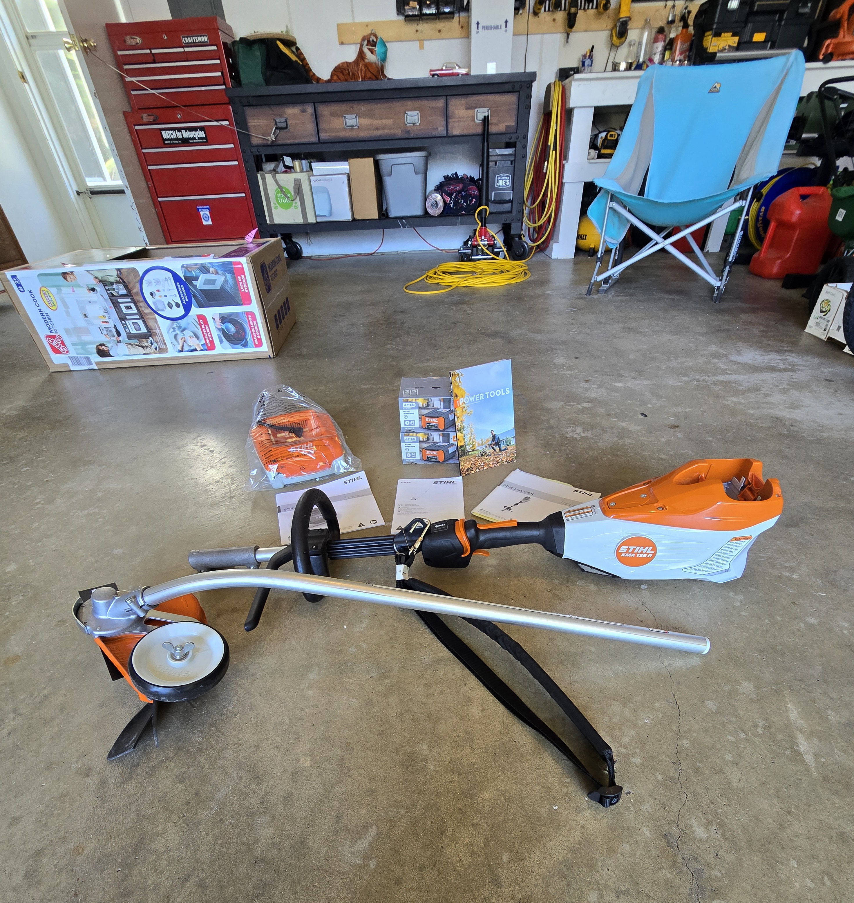 Close-up of the STIHL KMA 135 R twist-lock collar with trimmer and edger attachments laid out on a wooden workbench