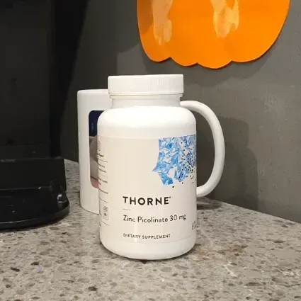 Thorne supplement bottle next to an NSF Certified for Sport certification card on a marble countertop.