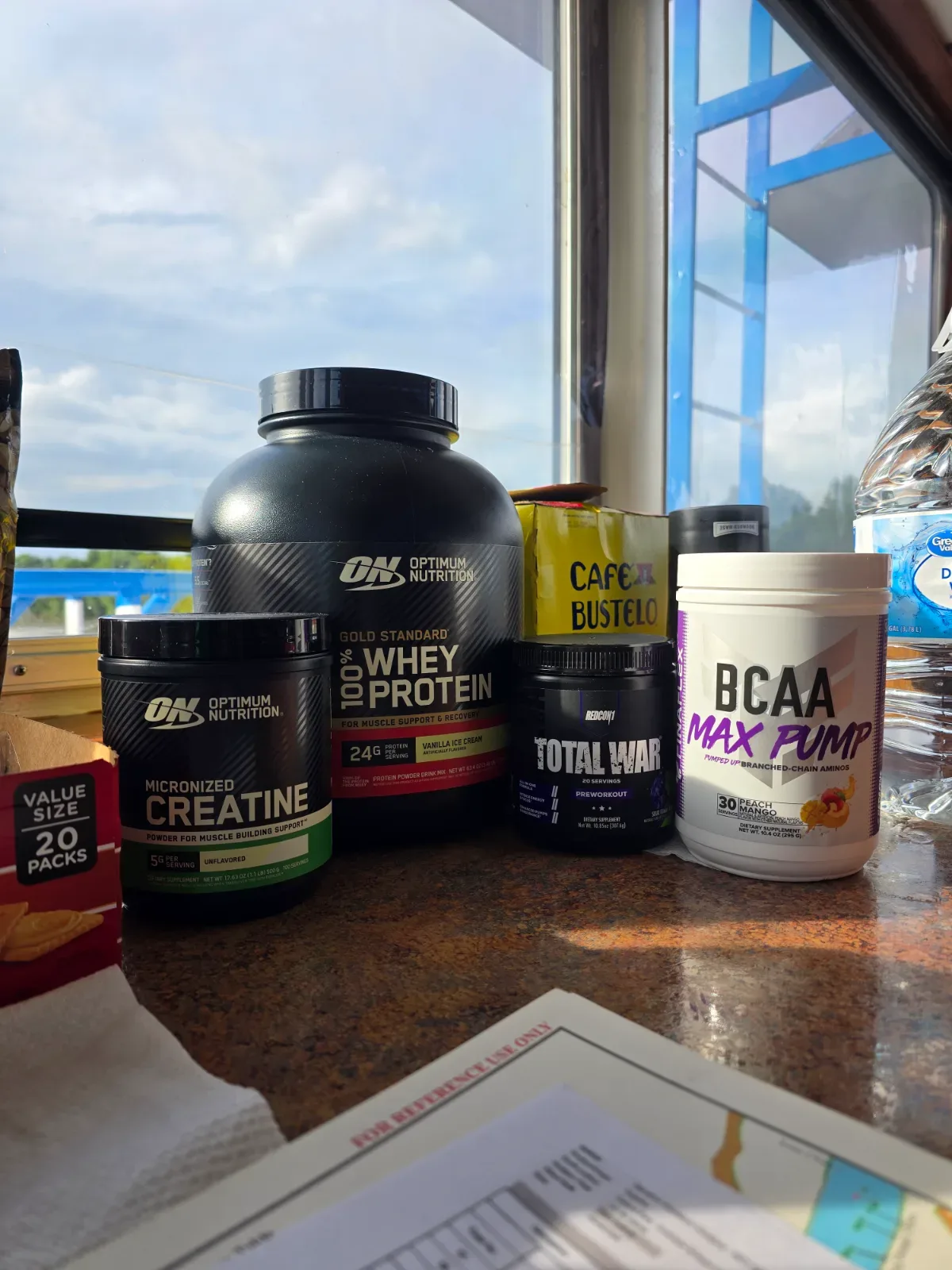 BCAA powder tub and shaker bottle sitting on a gym floor near weights