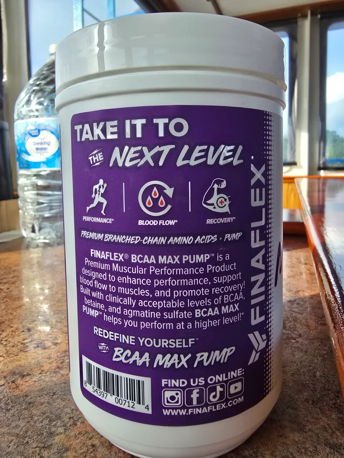 Scoop of BCAA powder resting beside a loaded barbell