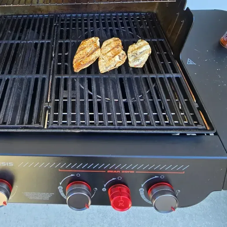 Weber Genesis E-330 Stealth with lid open showing lit burners and dedicated sear zone glowing orange