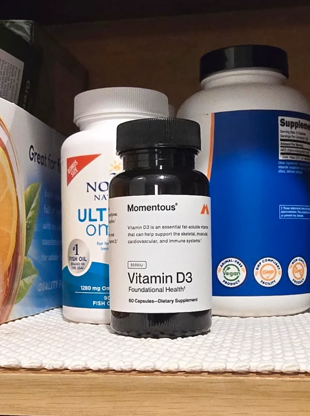 Momentous Vitamin D3 supplement bottle placed next to a printed blood panel lab results document.