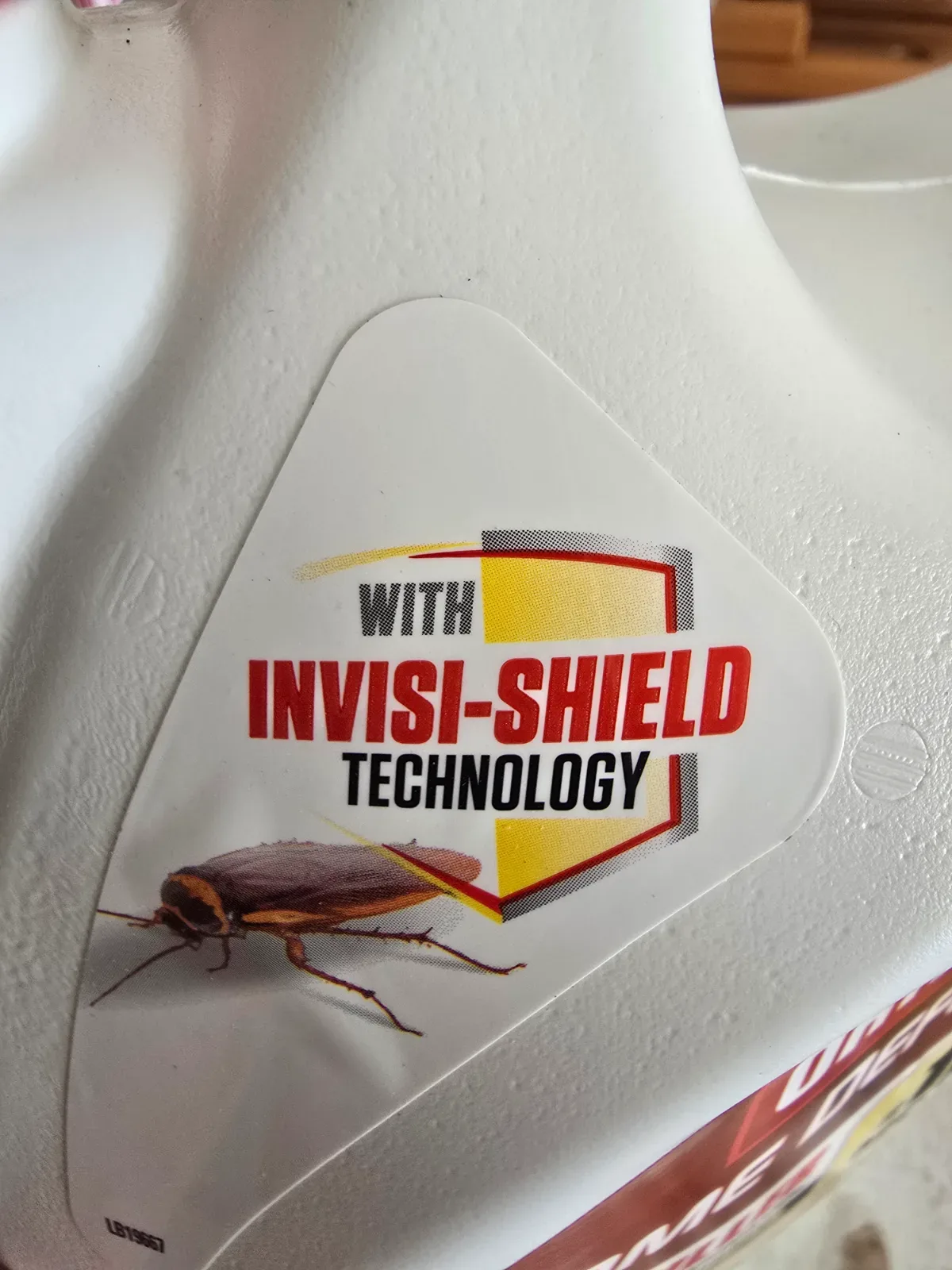 Ortho Home Defense jug stored upright under a kitchen sink alongside household cleaning supplies