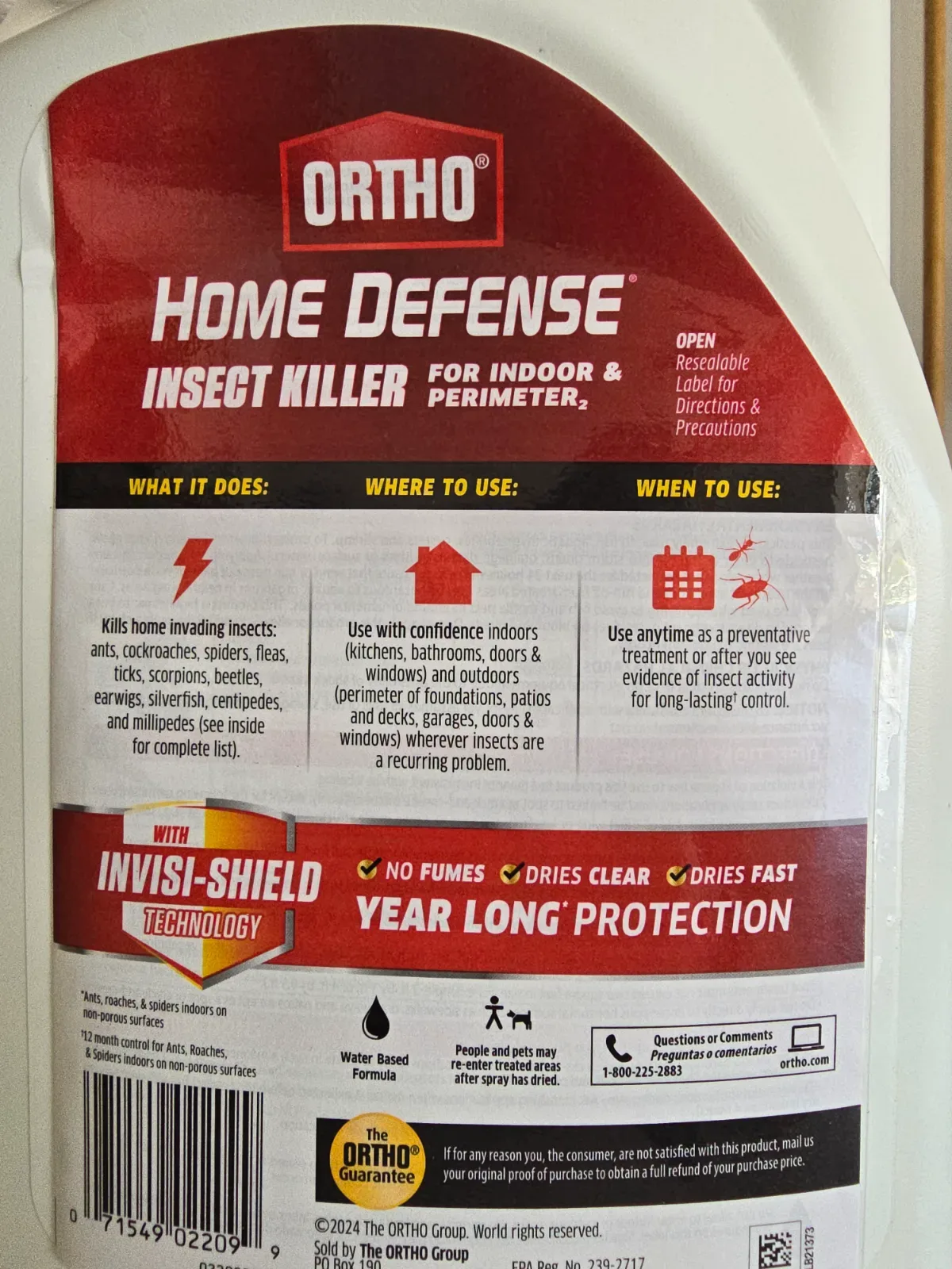 Ortho Home Defense gallon jug with extended wand applicator resting against a white interior baseboard