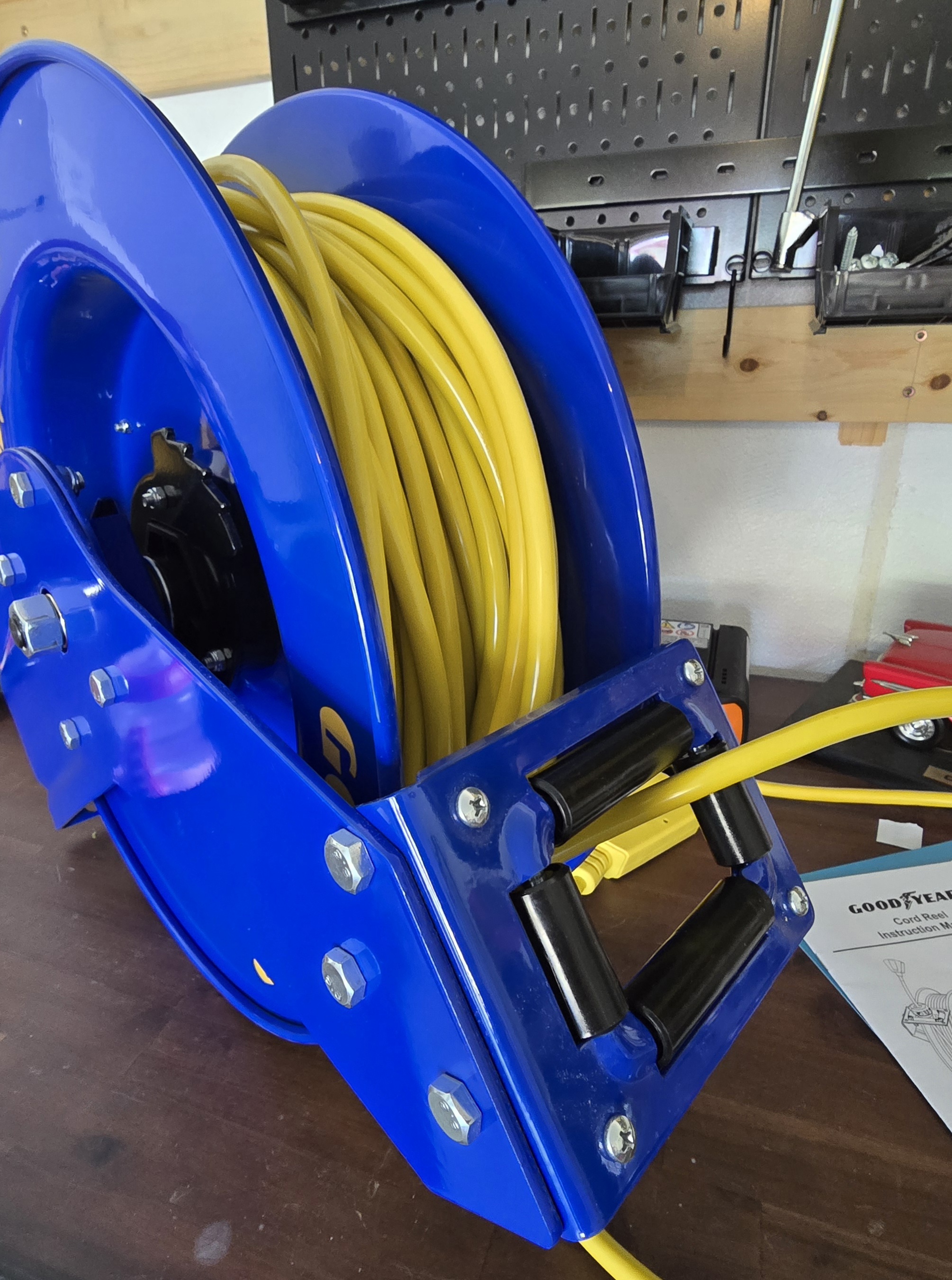 Close-up of the Goodyear cord reel lock mechanism with cord partially extended in a garage setting