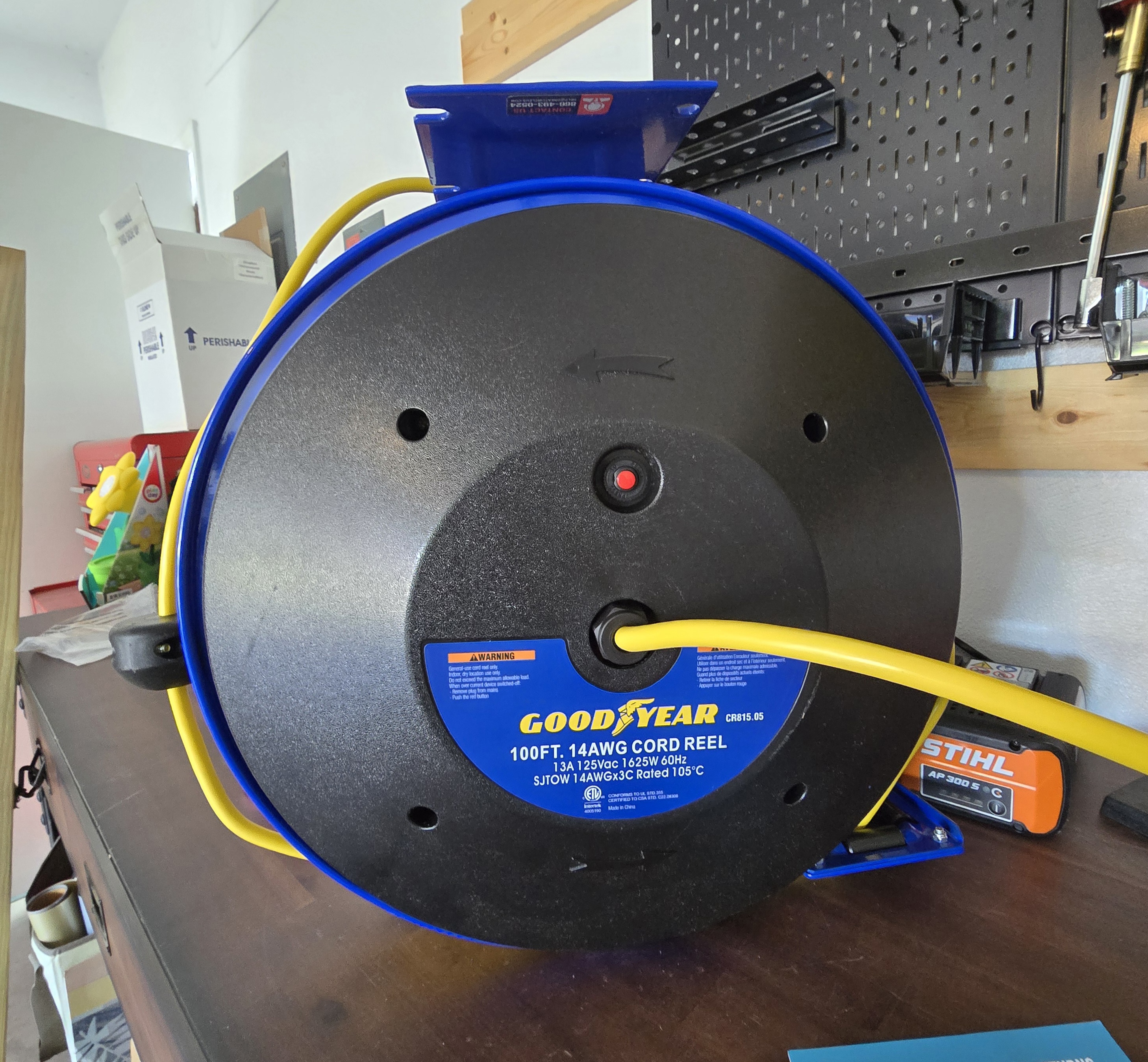 Goodyear cord reel with cord fully extended across garage floor and circular saw plugged into triple tap connector