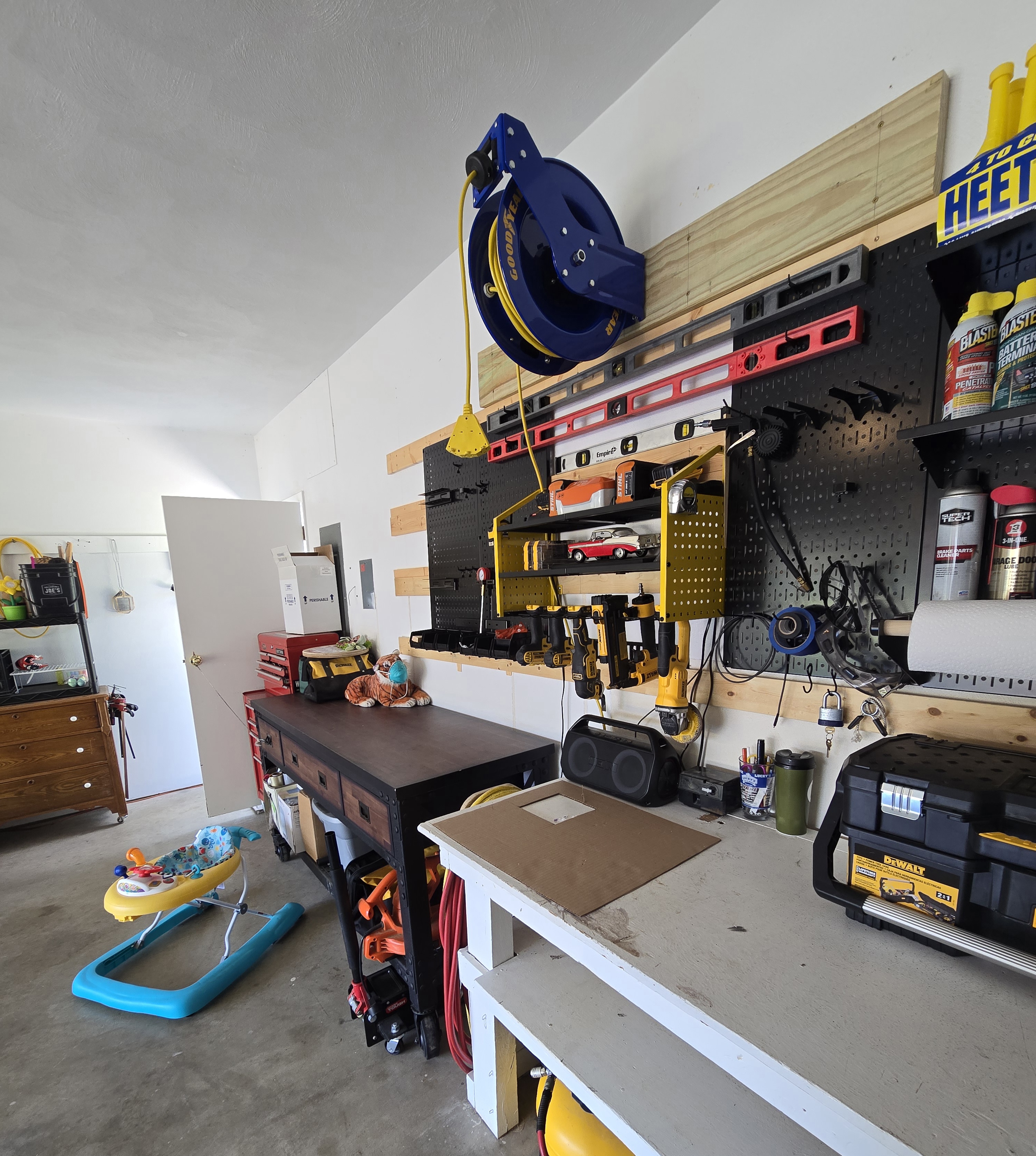 Goodyear 100ft cord reel secured to garage wall inside a working garage with pegboard tools behind