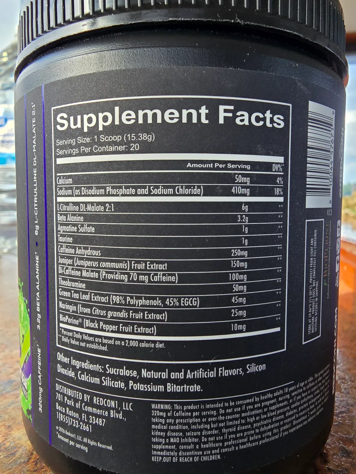 Scoop of pre-workout powder resting on the rim of an open supplement tub