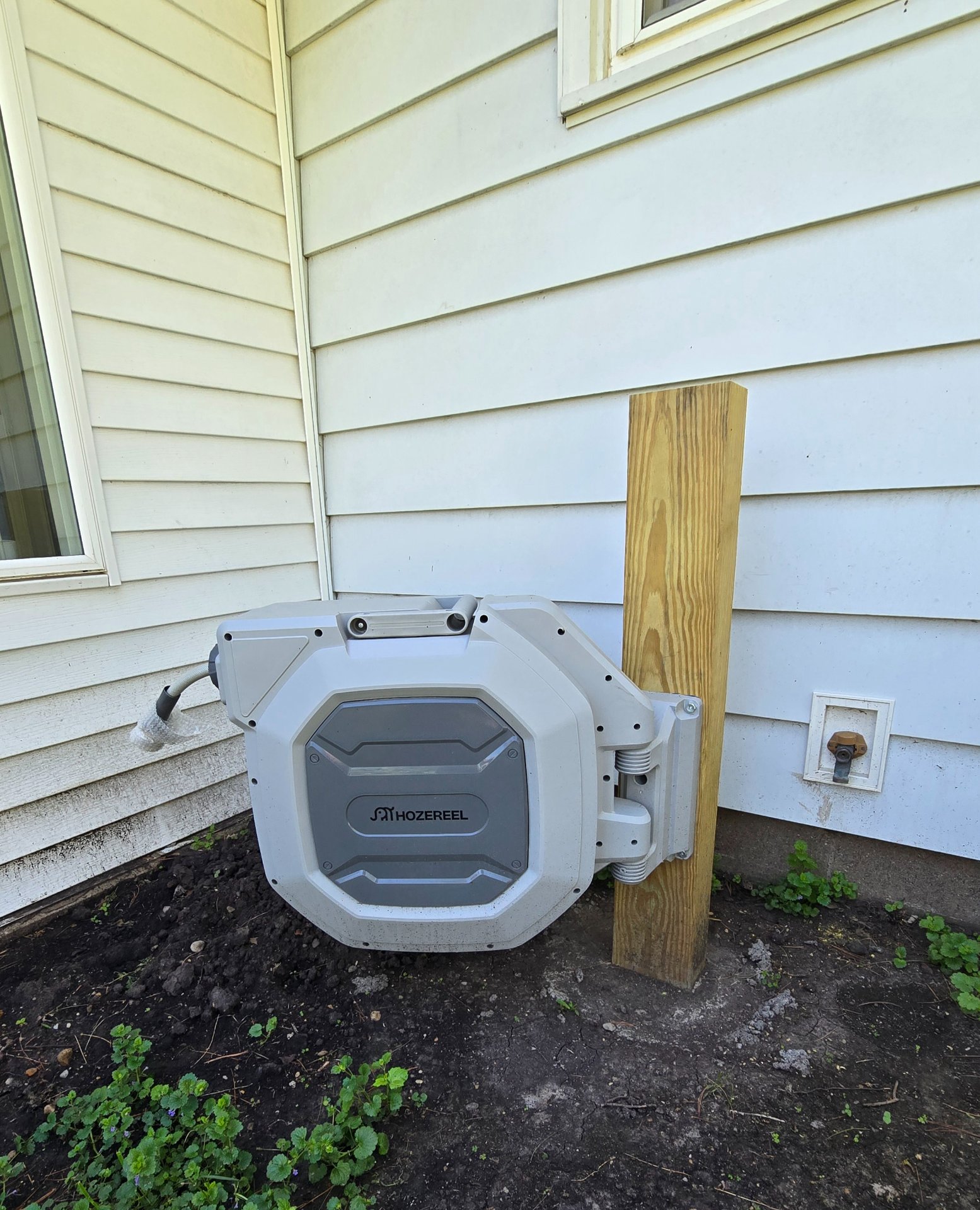 Hozereel hose reel with extended hose reaching toward a parked vehicle in a residential driveway